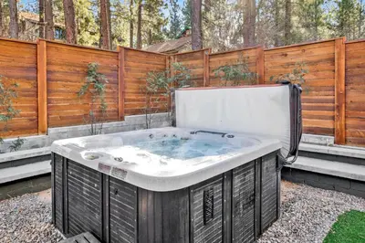 a hot tub in a backyard with a wooden fence at Oriole House- Walk to Lake Chalet w/ Hot Tub in Big Bear Lake