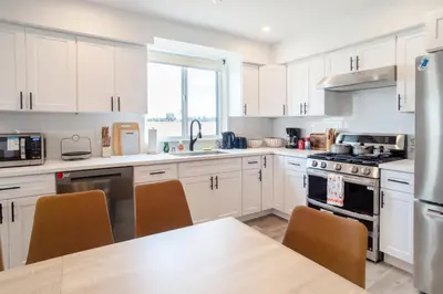 a kitchen with white cabinets and a table with chairs at Urban Oasis in the Heart of LA Near USC & Major Attractions in Los Angeles