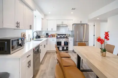 a kitchen with white cabinets and a table with chairs at Urban Oasis in the Heart of LA Near USC & Major Attractions in Los Angeles