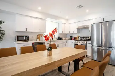 a kitchen with a wooden table and a stainless steel refrigerator at Urban Oasis in the Heart of LA Near USC & Major Attractions in Los Angeles