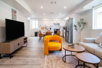 a living room with a tv and a yellow chair at Chic & Comfortable Space Near Downtown LA & USC in Los Angeles
