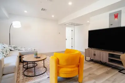 a living room with a yellow chair and a tv at Chic & Comfortable Space Near Downtown LA & USC in Los Angeles