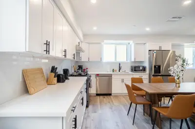 a kitchen with white cabinets and a wooden table at Stylish & Cozy Retreat Near USC & Downtown LA in Los Angeles
