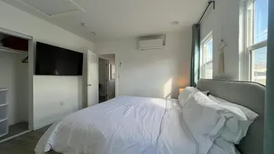 a bedroom with a white bed and a flat screen tv at Spacious 3BR 3BA Home Private Yard in Culver City in Los Angeles