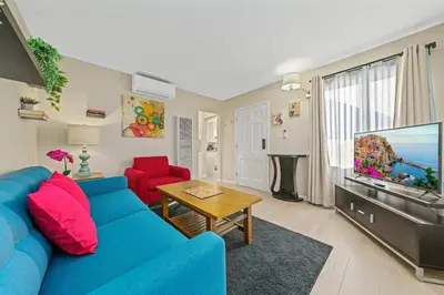 a living room with a blue couch and a flat screen tv at Comfy 2 BR House near LAX, SOFI and Intuit Dome! in Inglewood