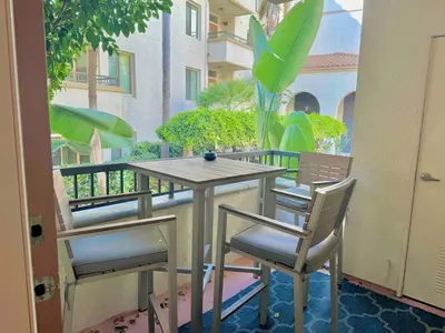 a wooden table and chairs on a balcony at Surfs up! Cozy 1 Bedroom Condo with Fountain View in Los Angeles