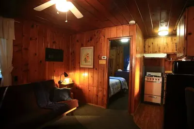 a bedroom with wooden walls and a bed and a couch at Sleepy Hollow Cabins and Hotel in Crestline