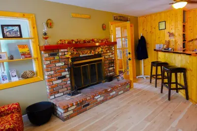 a living room with a brick fireplace and stools at Sleepy Hollow Cabins and Hotel in Crestline