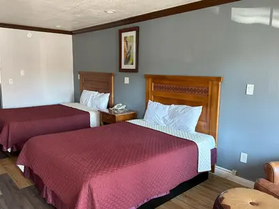 a hotel room with two beds with red sheets at Corona inn in Corona