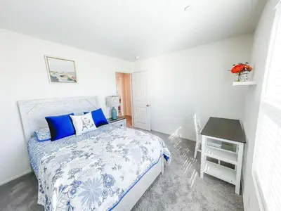 a white bedroom with a bed and a table at California 3-Bedroom Desert Escape With Garden in Victorville