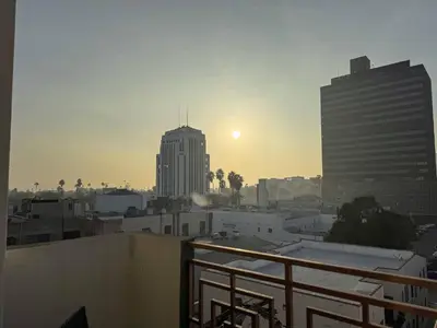a view of a city at sunset from a balcony at Bright & Spacious in Iconic LA Neighborhood Free parking - 10mins to Cedars in Los Angeles