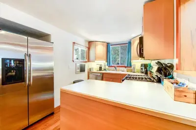a kitchen with a stainless steel refrigerator and wooden cabinets at Calm Cozy 3BR cabin wAC, WiFi, Parking, BBQ in Cedar Glen