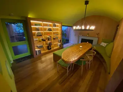a living room with a wooden table and a green couch at The Bernardi House in Los Angeles