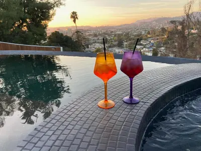 two wine glasses sitting on the edge of a swimming pool at The Bernardi House in Los Angeles