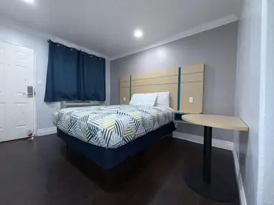 a small bedroom with a bed and a table at Uptown Inn in Long Beach