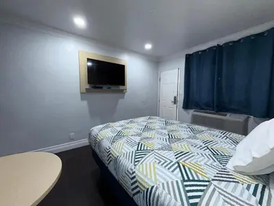 a bedroom with a bed and a tv on the wall at Uptown Inn in Long Beach