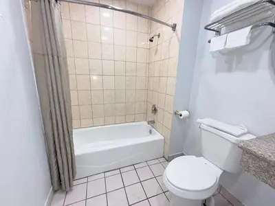 a bathroom with a toilet and a tub and a sink at Uptown Inn in Long Beach