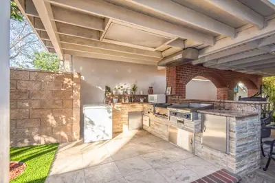 an outdoor kitchen with a stone wall and appliances at Peaceful Oasis in Anaheim