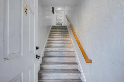 a stairway with a wooden rail and a white wall at 7 Mi to Downtown East Los Angeles Apartment in East Los Angeles