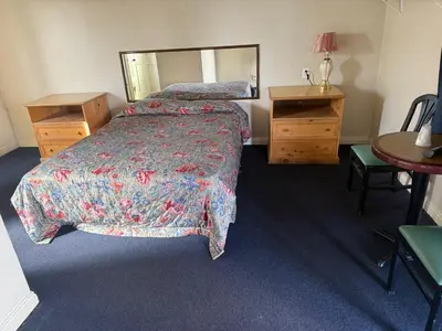 a hotel room with a bed and a mirror at El Rancho Motel, Pasadena in Pasadena