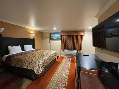 a hotel room with a bed and a flat screen tv at Sunrise Inn in Gardena