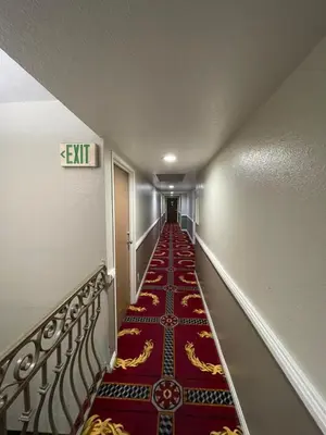 a long hallway with a red carpet on the floor at Sunrise Inn in Gardena