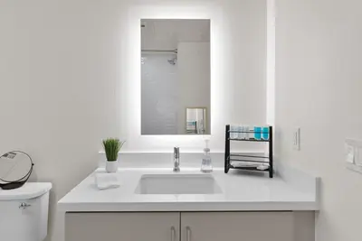 a white bathroom with a sink and a mirror at Bright Studio on Sunset Blvd Pool, Parking, Gym in Los Angeles