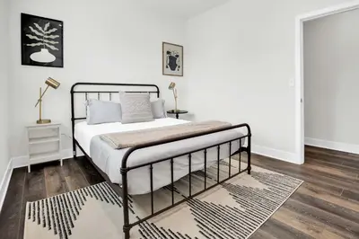 a bedroom with a bed with white walls and wood floors at LA Rooftop Paradise 2 in Los Angeles