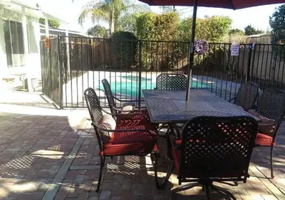 a table and chairs with an umbrella in front of a pool at MagicwayVillas Mickey's Pool Club House - Pool & Spa - Walking to Disneyland in Anaheim