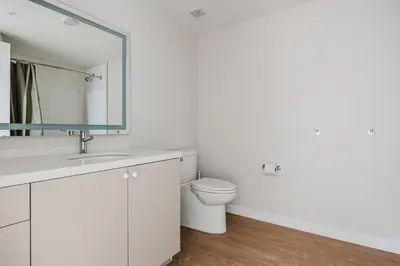 a white bathroom with a toilet and a mirror at Blueground Downtown elevator nr parks LAX-1240 in Los Angeles