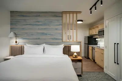 a bedroom with a large white bed and a kitchen at TownePlace Suites by Marriott Palmdale in Palmdale