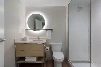 a bathroom with a toilet and a sink and a mirror at TownePlace Suites by Marriott Palmdale in Palmdale