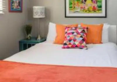 a bedroom with a white bed with orange pillows at MagicwayVillas TeaCup Pool House - Walking Distance to Disneyland in Anaheim