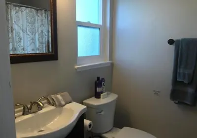 a bathroom with a toilet and a sink and a window at Magicwayvillas Micky's HideAway in Fullerton