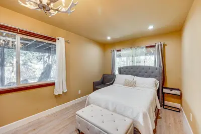 a bedroom with a bed and a chair and a chandelier at Wraparound Deck and Grill Wrightwood Cabin Near PCT in Wrightwood