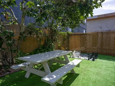 a picnic table in a garden with a cat sitting next to it at Fire Pit & Game Room 4 Beds Near Beach, LAX & SoFi in Lawndale