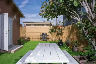 a backyard with a white bench in the grass at Fire Pit & Game Room 4 Beds Near Beach, LAX & SoFi in Lawndale