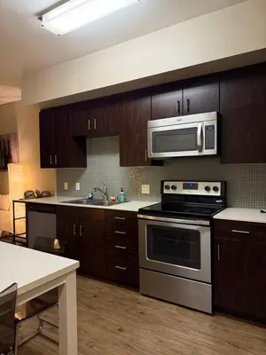 a kitchen with stainless steel appliances and wooden cabinets at Wilshire La Brea Apartments in Los Angeles