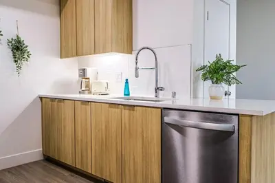 a kitchen with wooden cabinets and a stainless steel sink at Spacious 2BDR in SM - 5 minutes walk to the beach! in Los Angeles