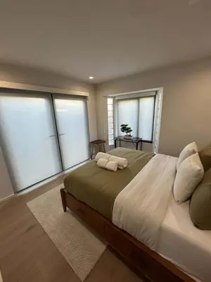 a bedroom with a large bed with four windows at Zenice Beach Luxury Home - Sauna, Cold Plunge, Spa in Los Angeles