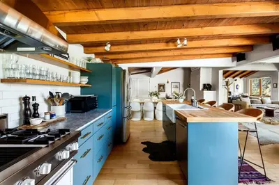 a kitchen with blue cabinets and wooden ceilings at Hillside Hideaway with Deck And Spa in Topanga Canyon in Topanga