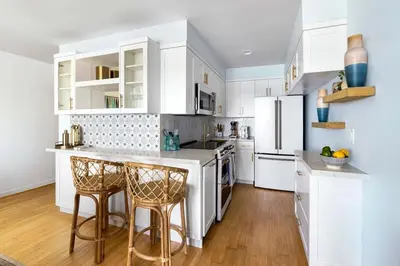a white kitchen with white cabinets and bar stools at Breathe Malibu Ocean Front Condo with Beach Access in Malibu