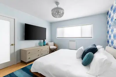 a bedroom with a white bed and a flat screen tv at Breathe Malibu Ocean Front Condo with Beach Access in Malibu