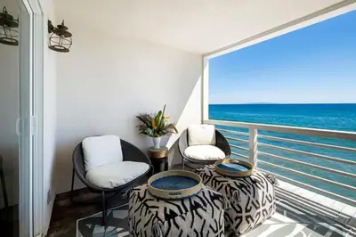 a balcony with two chairs and a table and the ocean at Breathe Malibu Ocean Front Condo with Beach Access in Malibu