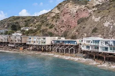 a group of houses on a pier next to the water at Breathe Malibu Ocean Front Condo with Beach Access in Malibu