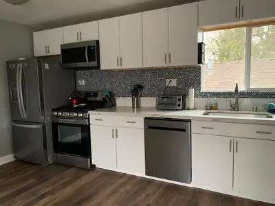 a kitchen with white cabinets and stainless steel appliances at The Lookout in Los Angeles
