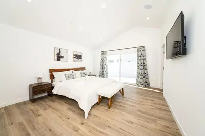 a white bedroom with a bed and a tv at A Brand New Home In Los Angeles in Van Nuys County Court Heliport