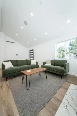 a living room with two green couches and a coffee table at A Brand New Home In Los Angeles in Van Nuys County Court Heliport
