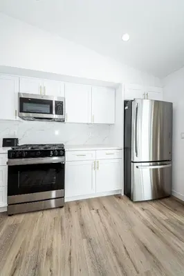 a kitchen with white cabinets and a stainless steel refrigerator at A Brand New Home In Los Angeles in Van Nuys County Court Heliport