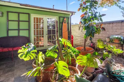 a green house with plants and a surfboard at Steps to Venice Beach Vintage Venice Retreat in Los Angeles